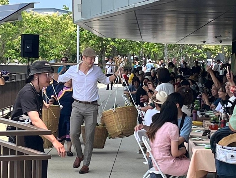 臺灣客家文化館賞桐食在地，由美籍歌手賈斯汀攜手苗栗在地大襟客文化藝術團成員挑擔宴席所使用的在地食材入場